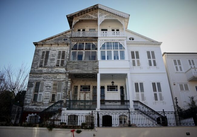 A historic semi-detached house on the Marmara island of Heybeliada near Istanbul. The right half of the house was maintained and painted white, the right is run down. Greek architecture in Turkey, woo historical building