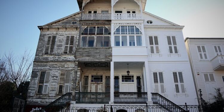 A historic semi-detached house on the Marmara island of Heybeliada near Istanbul. The right half of the house was maintained and painted white, the right is run down. Greek architecture in Turkey, woo historical building